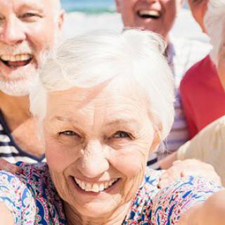 A group of senior friends smiling happily outdoors.