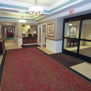 A spacious hotel lobby featuring a reception desk, artwork on the walls, and decorative ceiling lights.