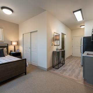 A modern studio apartment featuring a cozy bedroom area and a compact kitchen with minimalist decor.