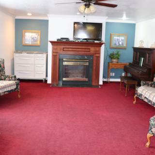 A cozy living room featuring a fireplace, red carpet, and elegant furniture.