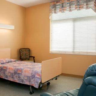 A simple room with a hospital bed, chair, and window.