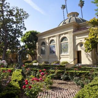 A beautiful garden with a historic building in the background, surrounded by lush greenery and vibrant flowers.