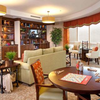A cozy and well-decorated living area with comfortable seating, bookshelves, and indoor plants.