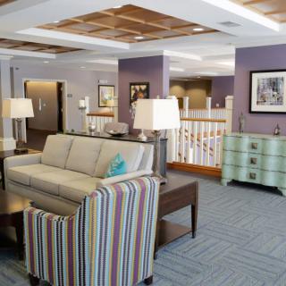 A cozy living room interior with a sofa, striped chairs, and table lamps.