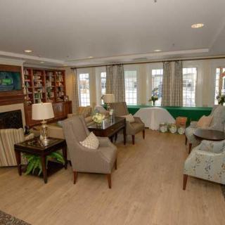 A cozy living room with comfortable armchairs, a fireplace, and a well-organized bookshelf.