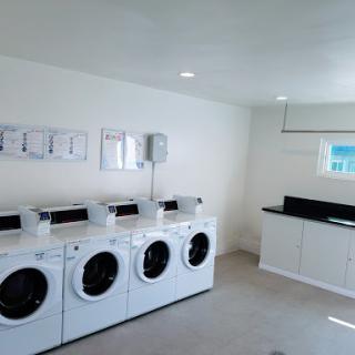 A modern and clean laundry room featuring multiple washing machines and a stylish black countertop.