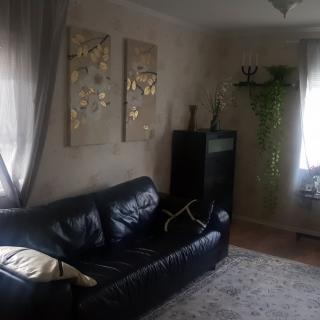 A cozy living room with a black leather sofa, wall art, and soft lighting.