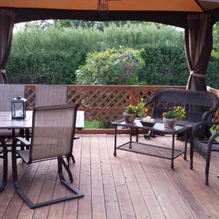 A cozy outdoor patio with seating and potted plants on a wooden deck.