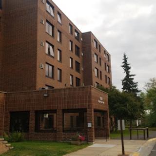 A multi-story residential building with a brick facade under a cloudy sky.