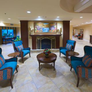 A cozy hotel lobby featuring elegant seating around a central fireplace.
