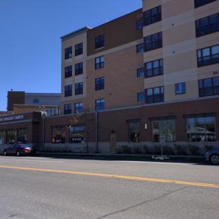 A modern multi-story building viewed from the street, showcasing its architecture and surrounding vehicles.