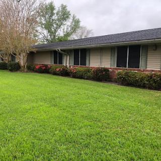 A charming residential house with a well-maintained lawn under a cloudy sky.