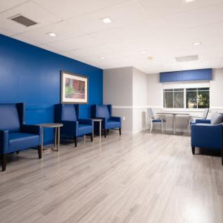 A modern waiting area featuring blue walls and comfortable seating, designed for a welcoming atmosphere.