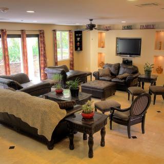 Spacious living room with multiple sofas, a TV, and coffee tables adorned with potted plants.