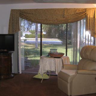 A cozy living room with an armchair facing a sliding glass door that offers a view of the outdoors.