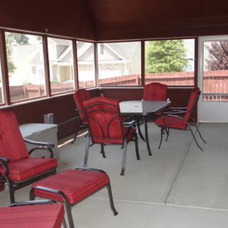 A screened patio with red-cushioned chairs and a table, offering an inviting outdoor seating area.