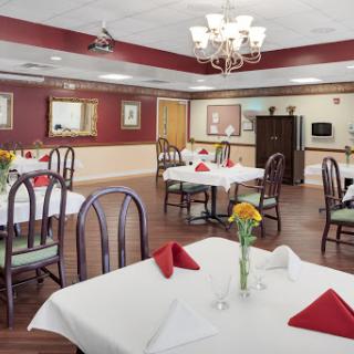 A cozy dining area set up for a meal, featuring elegantly arranged tables with red napkins and fresh flowers.