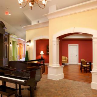 A beautifully decorated living room featuring a grand piano and elegant architectural details.