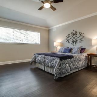 A cozy bedroom with a stylish bed, wooden flooring, and wall art.
