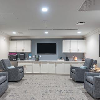 A modern waiting room with comfortable recliners and a central television.
