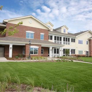 A large residential building with a well-maintained lawn and a clear blue sky.