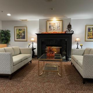 A cozy living room with two sofas facing each other around a glass coffee table and a fireplace adorned with artwork.