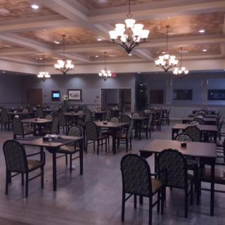 A spacious dining room with elegant chandeliers and neatly arranged tables and chairs.