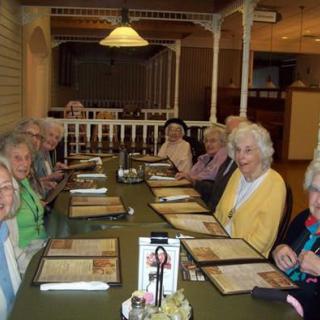 A group of seniors gathered around a table in a restaurant, looking at menus.