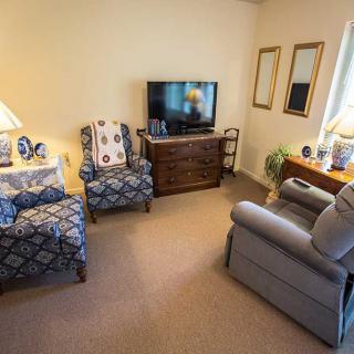 A cozy living room with armchairs, a TV, and decorative elements.