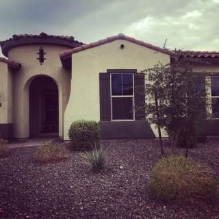 A southwestern style house with a stucco exterior and arched doorway surrounded by a desert landscape.
