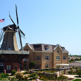 A picturesque view featuring a traditional windmill alongside a charming building, set against a clear blue sky.
