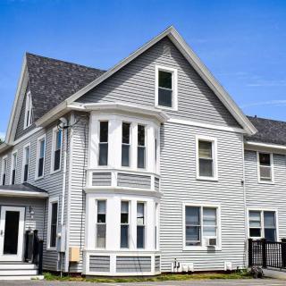 A two-story gray house with multiple windows under a clear blue sky.
