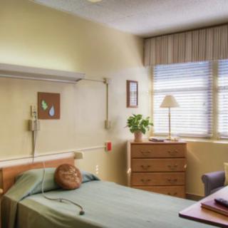 A hospital room with a bed, medical equipment, and a window with blinds.
