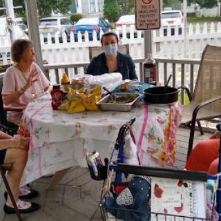 A small gathering of people enjoying food and conversation outdoors while observing safety protocols.