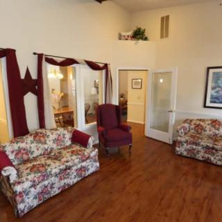 A cozy living room with floral upholstered furniture and wood flooring.