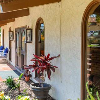 A charming building exterior featuring arched windows and lush potted plants.