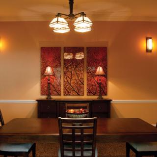 A cozy dining room with modern lighting and warm-toned artwork.