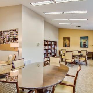 A cozy library reading area with tables, chairs, and bookshelves.