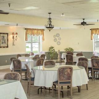 A spacious dining room with elegantly set tables and chairs, featuring classic decor and large windows for natural light.