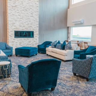 A modern living room with blue chairs, a white sofa, and a fireplace.