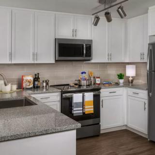 A modern kitchen with white cabinets, granite countertops, and stainless steel appliances.