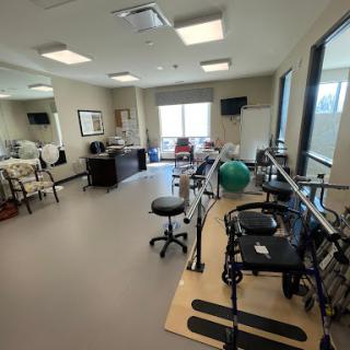 A spacious rehabilitation therapy room equipped with exercise equipment and natural lighting.
