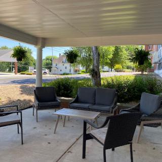 A cozy outdoor seating area with comfortable chairs and a table, surrounded by greenery.