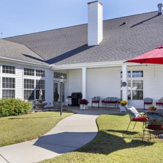 A cozy backyard patio with outdoor furniture and a red umbrella.