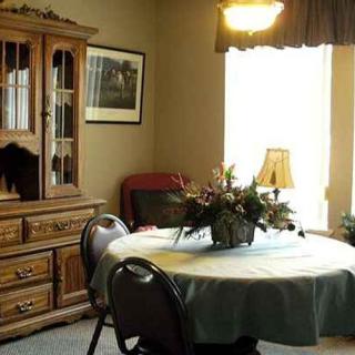 A cozy dining room with a round table, surrounded by chairs, and a wooden cabinet against the wall.