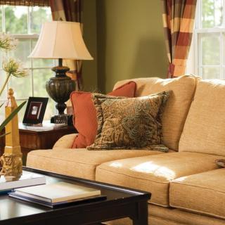 A cozy living room with a beige sofa, decorative cushions, and a side table with a lamp.