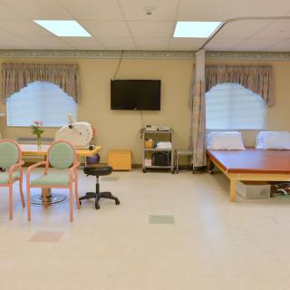A hospital room with a bed, television, and medical equipment.