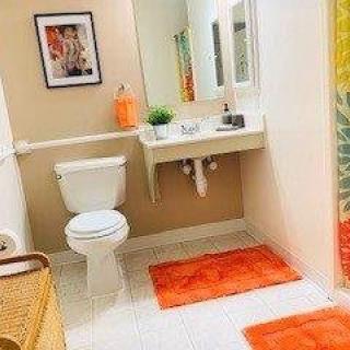 A modern bathroom with bright orange accents and clean white fixtures.