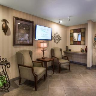 A cozy lobby area featuring comfortable chairs, a television, and decorative elements such as artwork and a mirror.