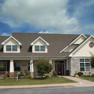 A modern suburban house with a well-maintained yard and a cloudy sky backdrop.